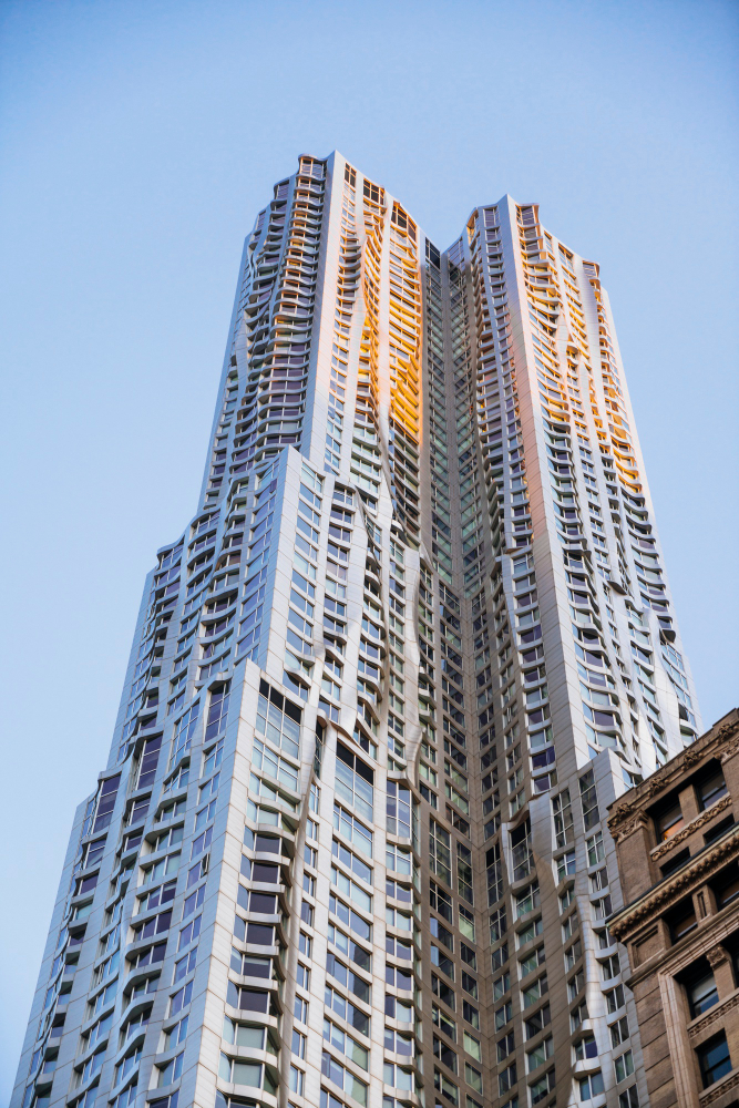 A modern high-rise building with a unique wavy architectural design, reflecting sunlight against a clear blue sky.