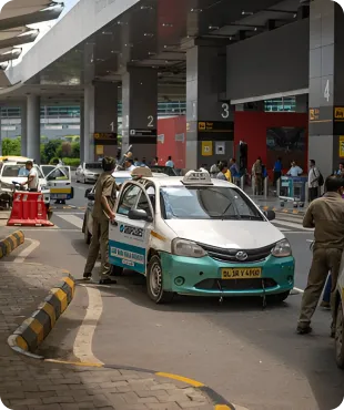 Taxi stand at a busy airport or transportation hub with multiple taxis and people walking in the background.